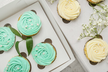 Boxes with tasty cupcakes and flowers, closeup