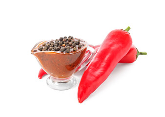Gravy boat with peppercorn sauce and chili peppers on white background