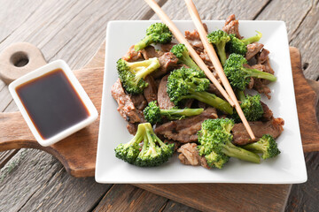 Plate with tasty beef and broccoli on wooden background