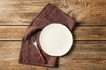 Obraz na płótnie Canvas Plate, fork and stylish napkin on wooden background