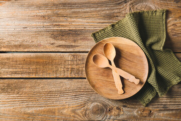 Plate, spoons and stylish napkin on wooden background