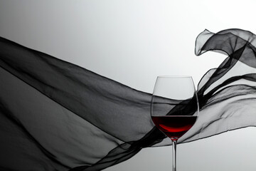 Glass of red wine on a background of waving black curtain.