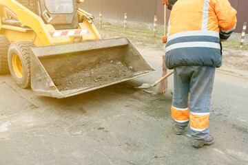 Traffic workers in bright orange reflective uniforms scrape off accumulated sand and debris between...