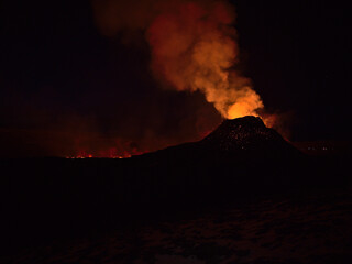 Stunning view of volcanic eruption in Geldingadalir valley near Fagradalsfjall mountain, Grindavík, Reykjanes peninsula, southwest Iceland in the night with red colored smoke and glowing lava.