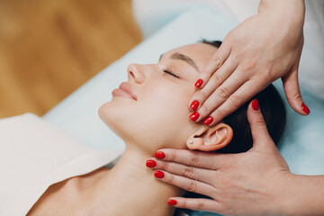 Brunette young woman getting face treatment massage at beauty spa salon