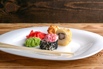 sushi rolls wasabi ginger and chopsticks on a plate on the table
