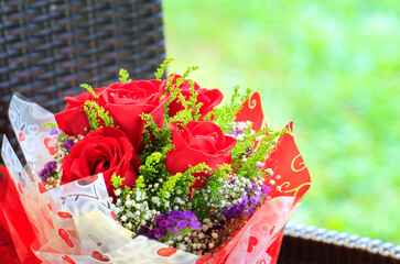 Red color roses hand bouquet on a chair. Copy space.
