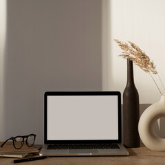 Aesthetic home office desk workspace with sunlight shadows on the wall. Blank screen laptop...