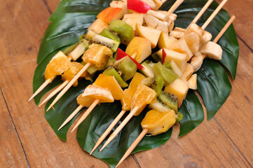 Fruit barbecue on leaf of monstera and wooden background 