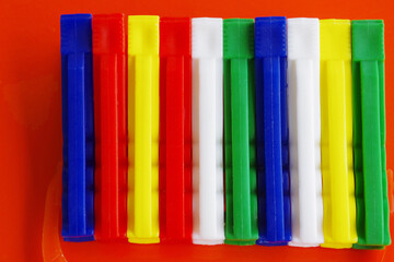 Colored plastic clothespins on red background.