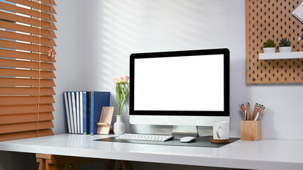 Modern home office with computer, books and office supplies on white table.