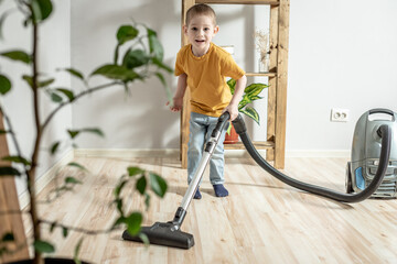 Little child helps his parents in housework, cleaning the floor using a vacuum cleaner
