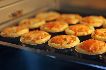 Mini pie from meat and mushrooms baking in industrial oven