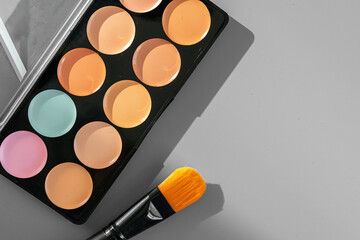 Make-up palette with colorful concealers on gray background