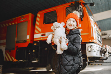 Girl near fire truck with a toy in hand