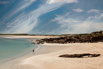 Young teenager girl walking on a warm sand of Gurteen beach, county Galway, Ireland. Warm sunny day. Cloudy sky. Outdoor activity concept. Beautiful Irish scenery in the background