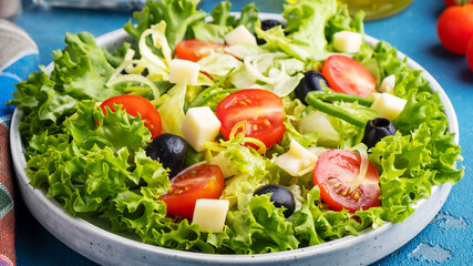 Diet and healthy salad with lettuce, tomatoes, cheese, black olives and onion. Closeup