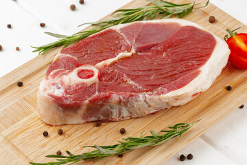 Raw lamb steak on board on white wooden table