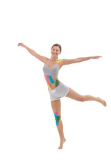 Kinesiology taping. Kinesiology tape on patient knee, belly, shoulder. Young female athlete doing exercises. Post traumatic rehabilitation, weight loss, cellulite removal, sport physical therapy.