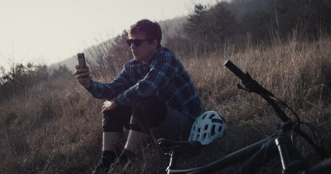 Mountain biker take smartphone photo wear sunglasses enjoy evening