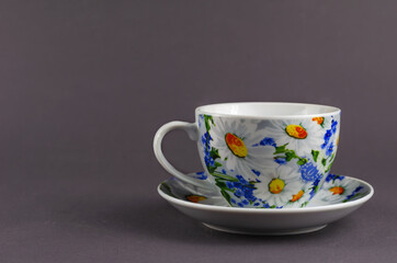 White cup with painted flowers on a gray background.