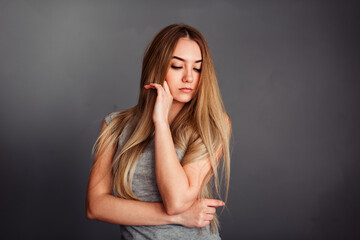 A girl with blue eyes looks piercingly into the frame, wrapping her hair in a gray background