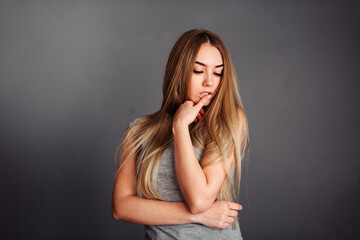 A girl with blue eyes looks piercingly into the frame, wrapping her hair in a gray background