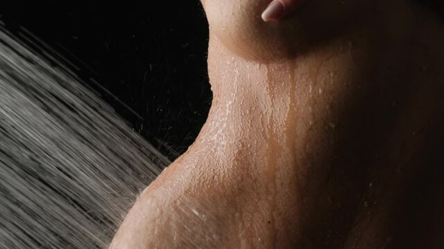 A girl with a beautiful figure in the shower on a black background.