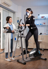 Performance scientist examining biomechanics of athlete runner on cross trainer. Team of researchers monitoring endurance, vo2 max, psychological resistance.