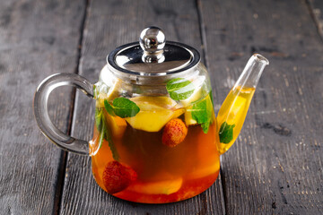 Glass teapot of herbal fruit tea with strawberry and mint