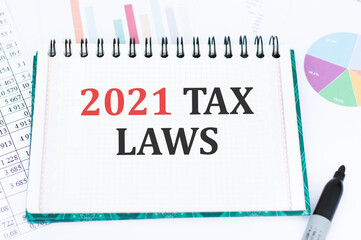 words TAX LAWS 2021 on a notebook against the background of graphs. Business concept.