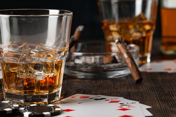 Playing poker with whiskey and cigars on table