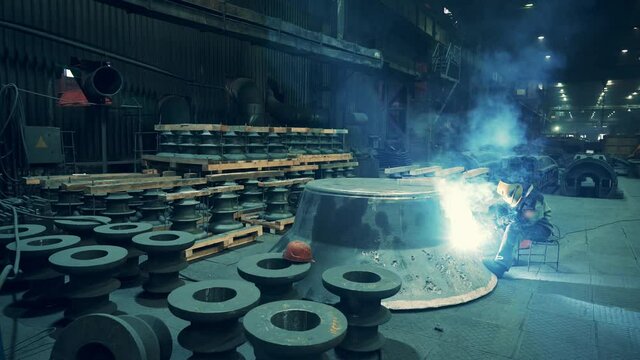 Metal welder working with arc welding machine at metallurgical foundry factory workshop interior. Metalwork manufacturing.