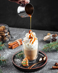 Pouring sweet coffee latte with caramel syrup on the new year decorated table
