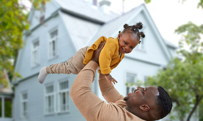 family, fatherhood and mortgage concept - happy african american father playing with baby daughter...