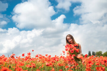 Fototapeta na wymiar Ukrainian girl in sportwear holding a bouquet of poppies in field