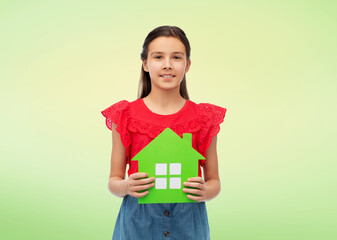 eco living, environment and sustainability concept - smiling little girl holding green house icon over natural background