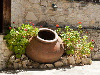 Big clay pot beside stone house wall