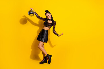 Fototapeta na wymiar Full size photo of young attractive black woman happy positive smile hold disco ball isolated over yellow color background