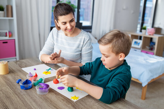 family, creativity and craft concept - mother and little son making picture of modeling clay at home