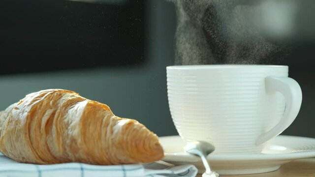 Coffee cup with steam. Hot coffee and croissant