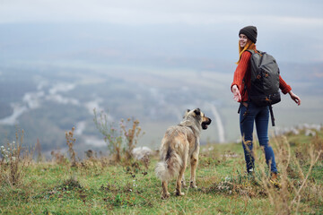 woman hiker with backpack with dog in the mountains travel friendship