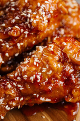 Closeup on asian fried chicken wings with sauce and sesame seeds texture