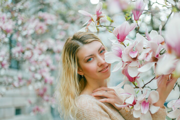 Beautiful young blonde near a blossoming Magnolia tree. Spring.