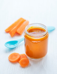 Baby carrot mashed with spoon in glass jar