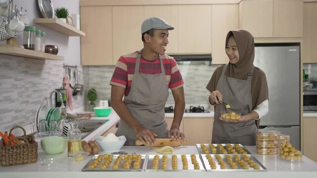 asian muslim couple making nastar snack cake together in the kitchen during ramadan for eid celebration mubarak with family. indonesian food traditonal