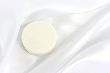 Fototapeta na wymiar White solid soap shampoo bar on silk background, bath cosmetics