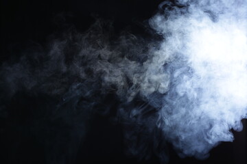 Illuminated smoke on black background in dark