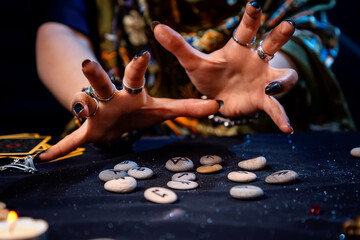 Female hands of a fortune teller reads scandinavian runes. The concept of divination, astrology and predicting the future
