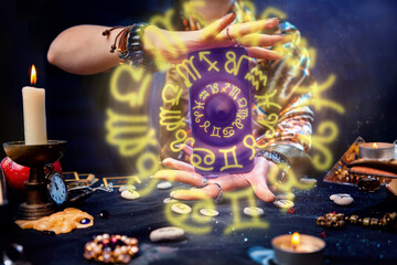 A fortune teller holds a smartphone in her hands, from which luminous zodiac circles fly out....